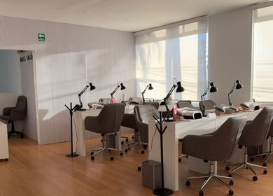 Área de atención moderna en Aura Nails Salón, Tijuana, Baja California, MX con sillas y lámparas elegantes.