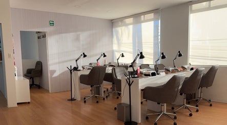 Área de atención moderna en Aura Nails Salón, Tijuana, Baja California, MX con sillas y lámparas elegantes.
