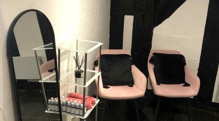 Elegant seating area at KM Sculpt & Glow in Congleton, England, GB with pink chairs and a mirror.