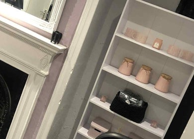 Elegant shelf display at KM Sculpt & Glow, Congleton, England, GB featuring decorative pink jars.