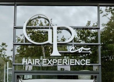GP Hair Experience entrance in Amsterdam, Noord-Holland, NL with stylish signage and reflections.