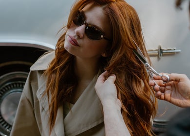 Stylist cuts red hair at GP Hair Experience, Amsterdam, Noord-Holland, NL, highlighting chic outdoor style.