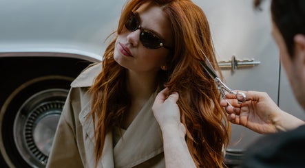 Stylist cuts red hair at GP Hair Experience, Amsterdam, Noord-Holland, NL, highlighting chic outdoor style.