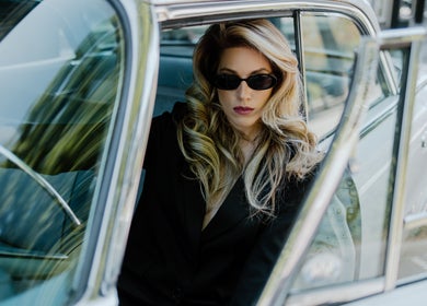 Stylish woman with sunglasses in vintage car at GP Hair Experience, Amsterdam, Noord-Holland, NL.