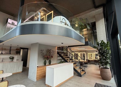 Modern, sleek interior of GP Hair Experience in Amsterdam, Noord-Holland, NL with glass balcony and plants.