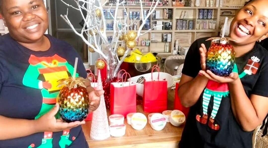 Smiling staff at Tiffany's Beauty Salon, Ballito, Kwazulu-natal, ZA, holding colorful drinks with festive decor.