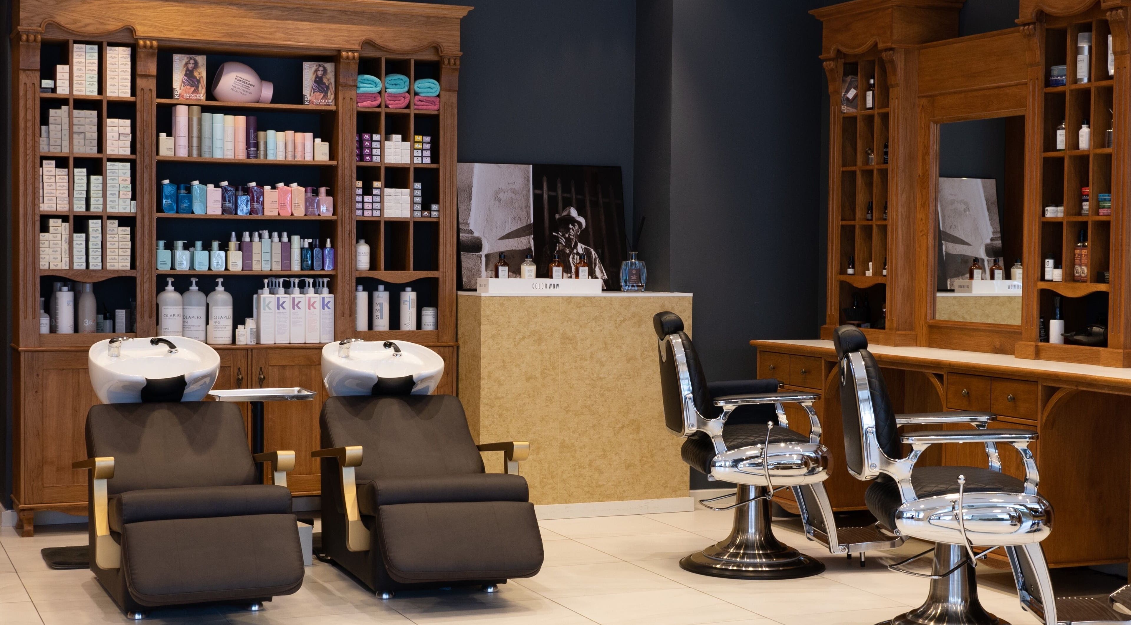 Binnenzicht van Blessed Cuts in Boxtel, Noord-Brabant, NL met retro kappersstoelen en producten op planken.