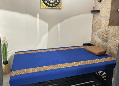 Unutrašnjost Oriental Massage Ragusa u Dubrovniku s plavim masažnim krevetom i ukrasima na zidu.