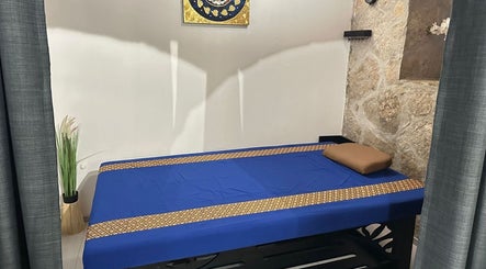 Unutrašnjost Oriental Massage Ragusa u Dubrovniku s plavim masažnim krevetom i ukrasima na zidu.