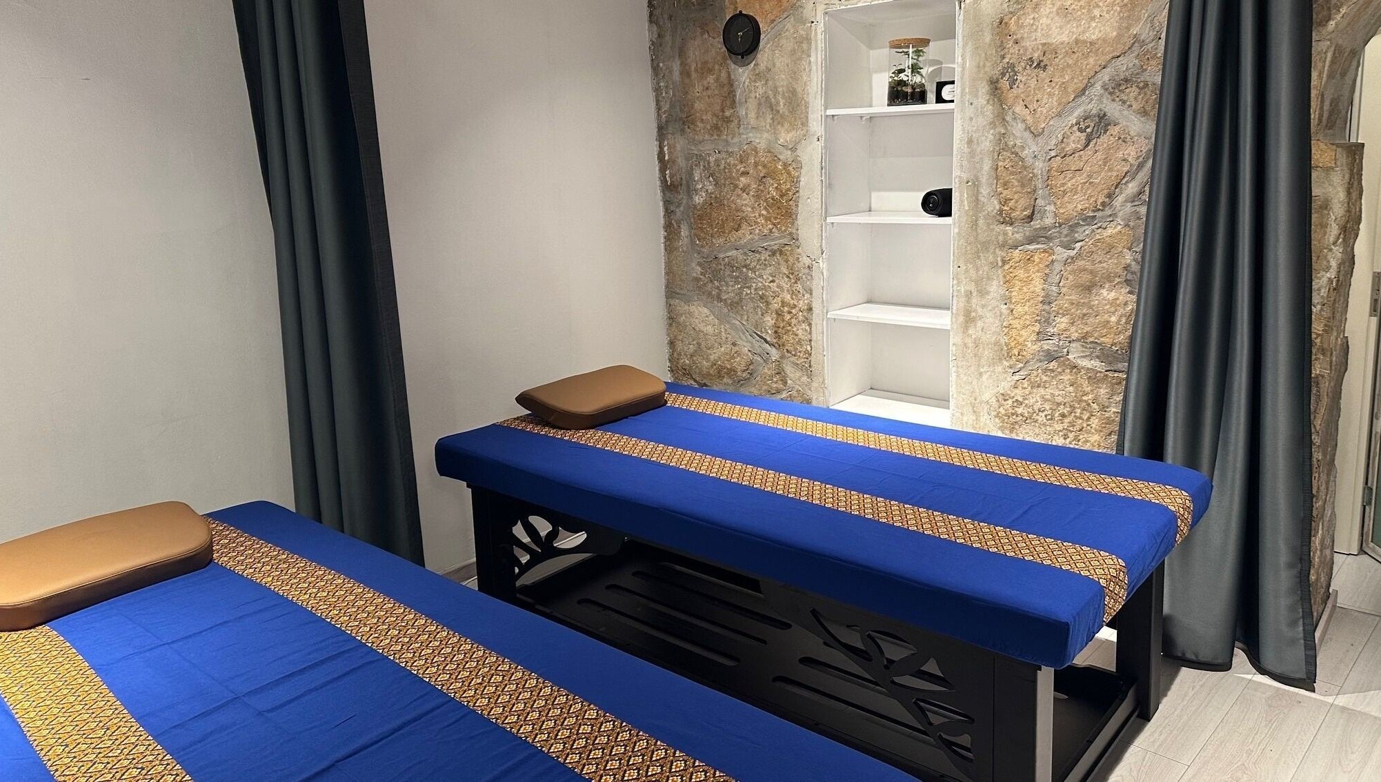 Unutrašnjost Oriental Massage Ragusa, Dubrovnik s dvije masažne ležaljke i kamenim zidovima.