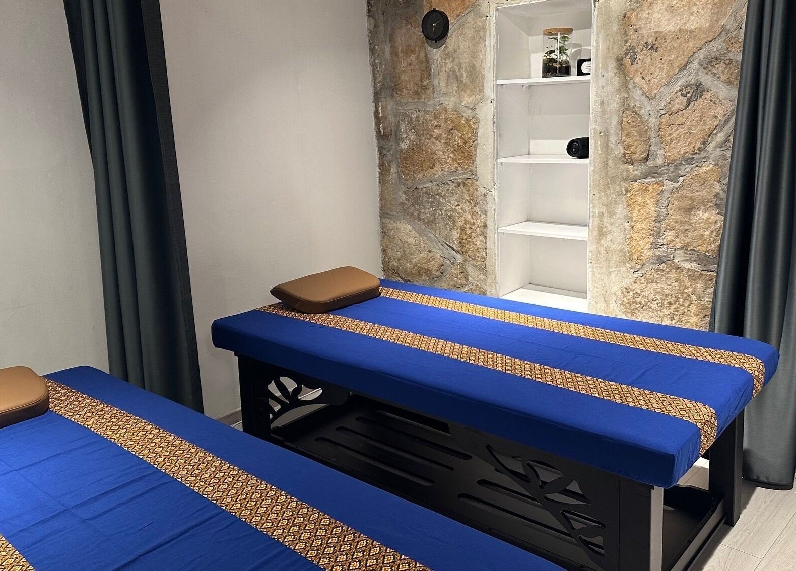 Unutrašnjost Oriental Massage Ragusa, Dubrovnik s dvije masažne ležaljke i kamenim zidovima.