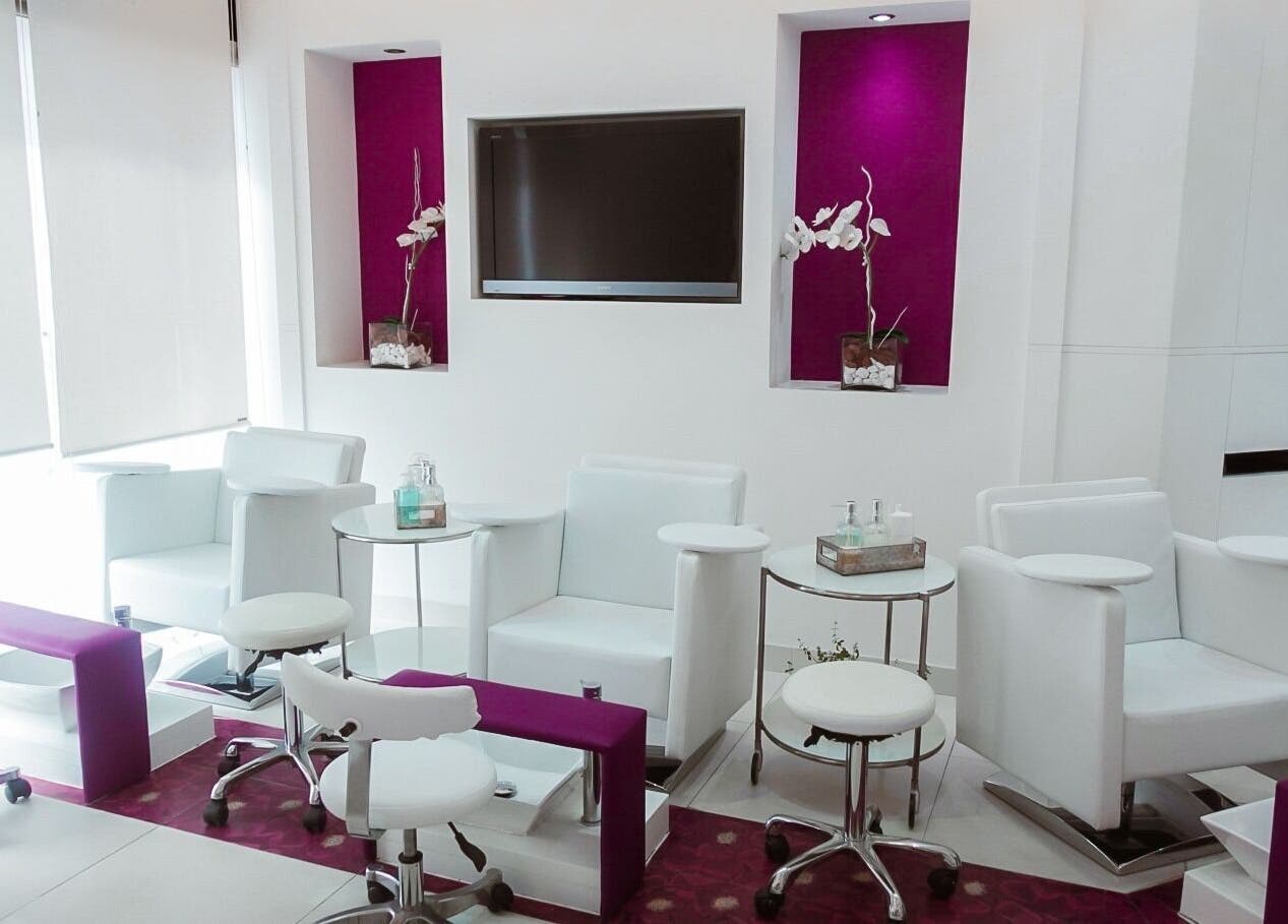 Elegant nail station at Nails Couture Ladies Salon in Abu Dhabi, featuring plush white chairs and vibrant accents.