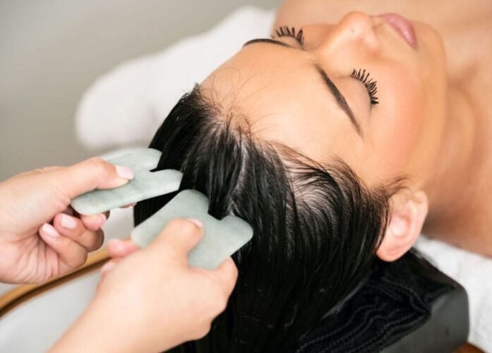 Woman receives a scalp massage with jade stones at Spa Eves | Scalp Spa + Massage in Austin, Texas, US.