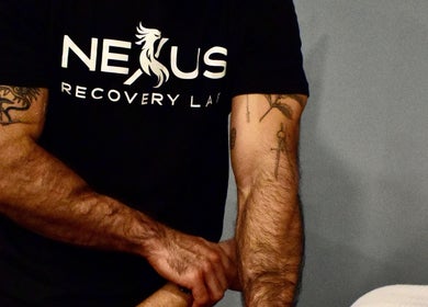 Therapist at Nexus Recovery Lab FTL giving a massage in Fort Lauderdale, Florida, US. Tattooed arms visible.