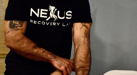 Therapist at Nexus Recovery Lab FTL giving a massage in Fort Lauderdale, Florida, US. Tattooed arms visible.