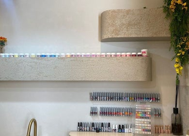 Nail polish shelf at Bali Nails & Lashes, Al Ain, Abu Dhabi, AE, showcasing vibrant colors in stylish decor.