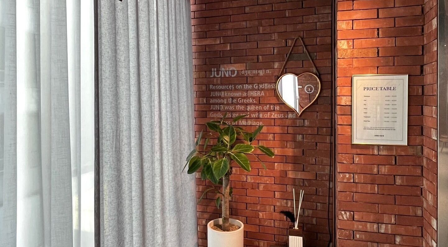 Warm brick wall with a heart-shaped mirror and plant at Juno Hair Myungdong 4, 서울특별시, 서울특별시, KR.