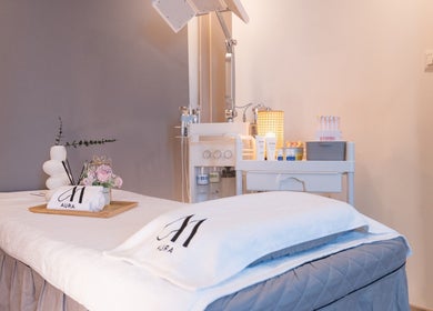 Luxury treatment room at AURA J Gateway Studio, Singapore, SG, featuring plush bed and premium skincare products.