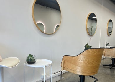 Elegant salon interior at DDIOR | HAIR | Richmond with stylish wood chairs and round mirrors in Richmond, Victoria, AU.