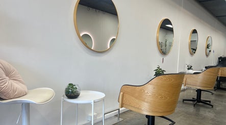 Elegant salon interior at DDIOR | HAIR | Richmond with stylish wood chairs and round mirrors in Richmond, Victoria, AU.