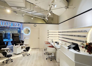 Interiören av Nail Haus Luleå i Luleå, Norrbottens Län med eleganta nagelstationer och flaska hyllor.