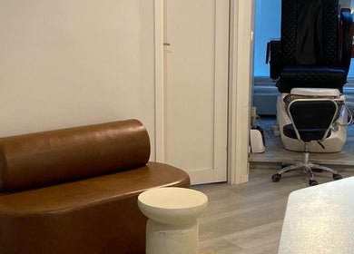 Väntområde hos Nail Haus Luleå, Luleå, Norrbottens Län, SE med elegant brun soffa och nagelstation.