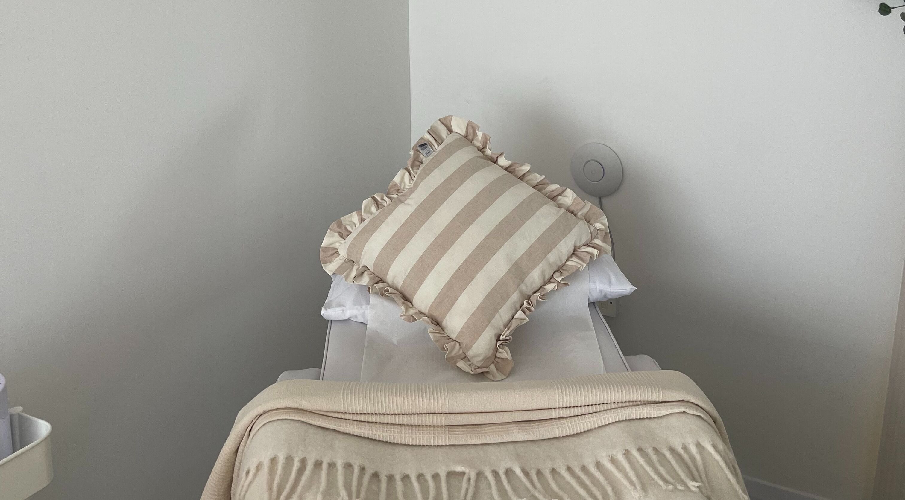 Cozy treatment bed at Leah Jane Beauty and Aesthetics in Rochester, England, GB, featuring a striped pillow.