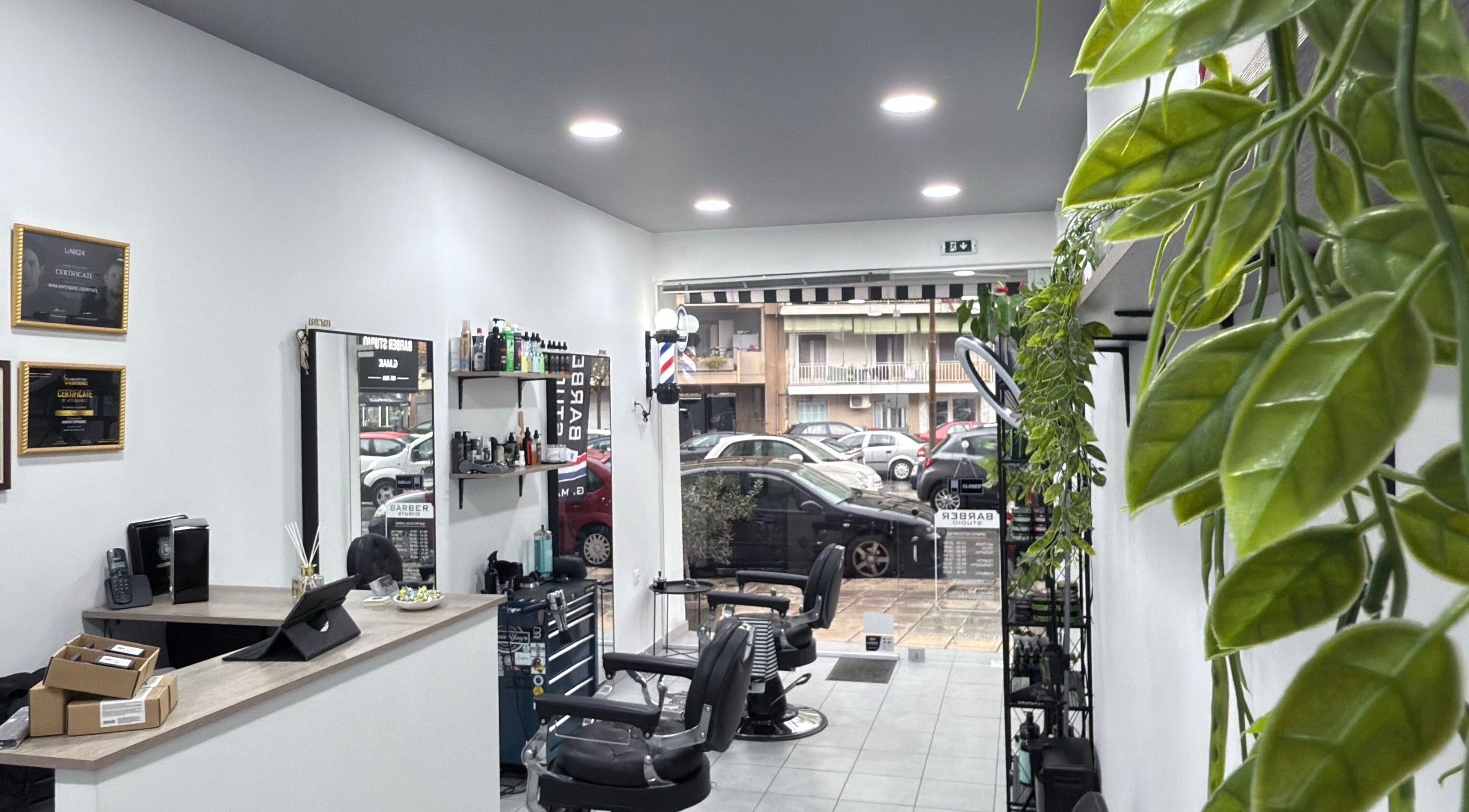 Εσωτερικό του G.Mak Barber Studio στη Λάρισα, GR με σύγχρονους καθρέφτες και πράσινα φυτά.