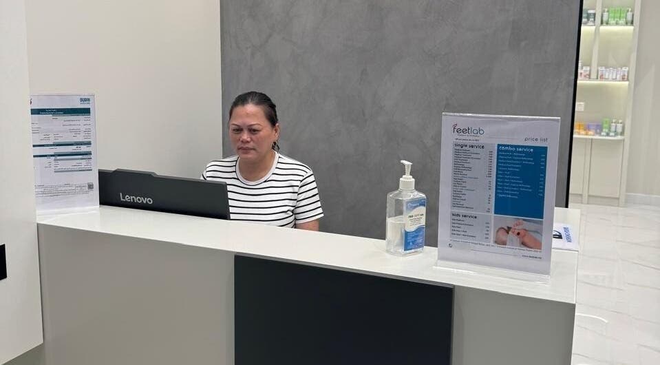 Reception desk of Feetlab - Dubai Creek Harbour, Dubai, AE with staff and service menu displayed.