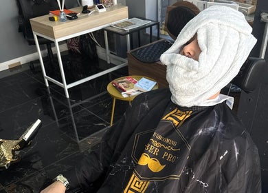 Client enjoying facial towel treatment at Epic barber Woking, located in Woking, England, GB.