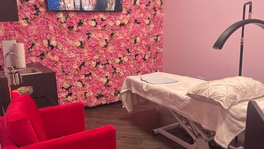 iSugaring spa room in Seminole, Florida, US, with floral wall, treatment bed, and red chair.