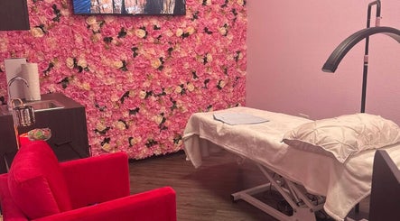 iSugaring spa room in Seminole, Florida, US, with floral wall, treatment bed, and red chair.