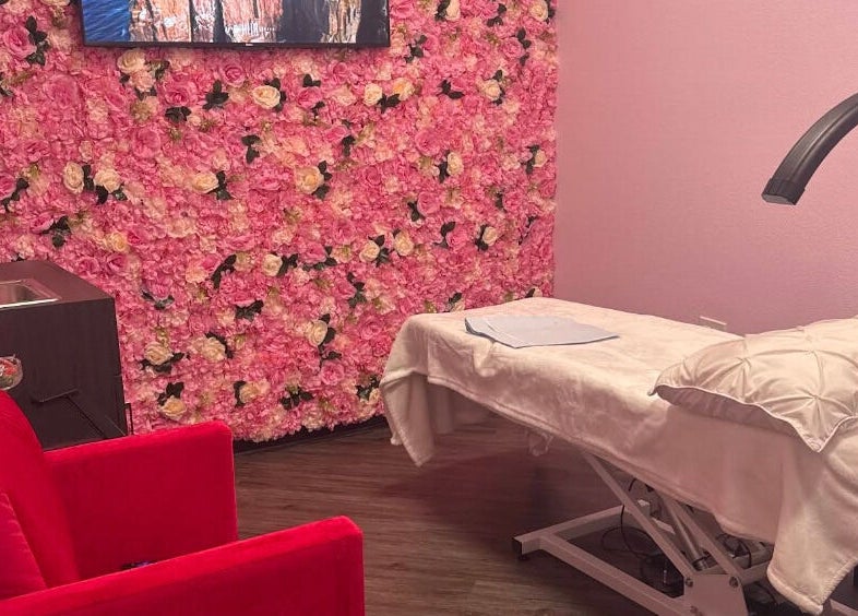 Chic treatment room with pink floral wall at iSugaring, Seminole, Florida, US. Features a cozy treatment table.