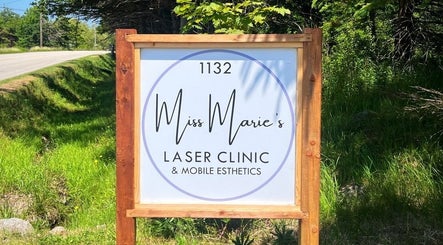 Entrance sign for Miss Marie’s Laser Clinic in Brooklyn, Nova Scotia, CA, surrounded by lush greenery.