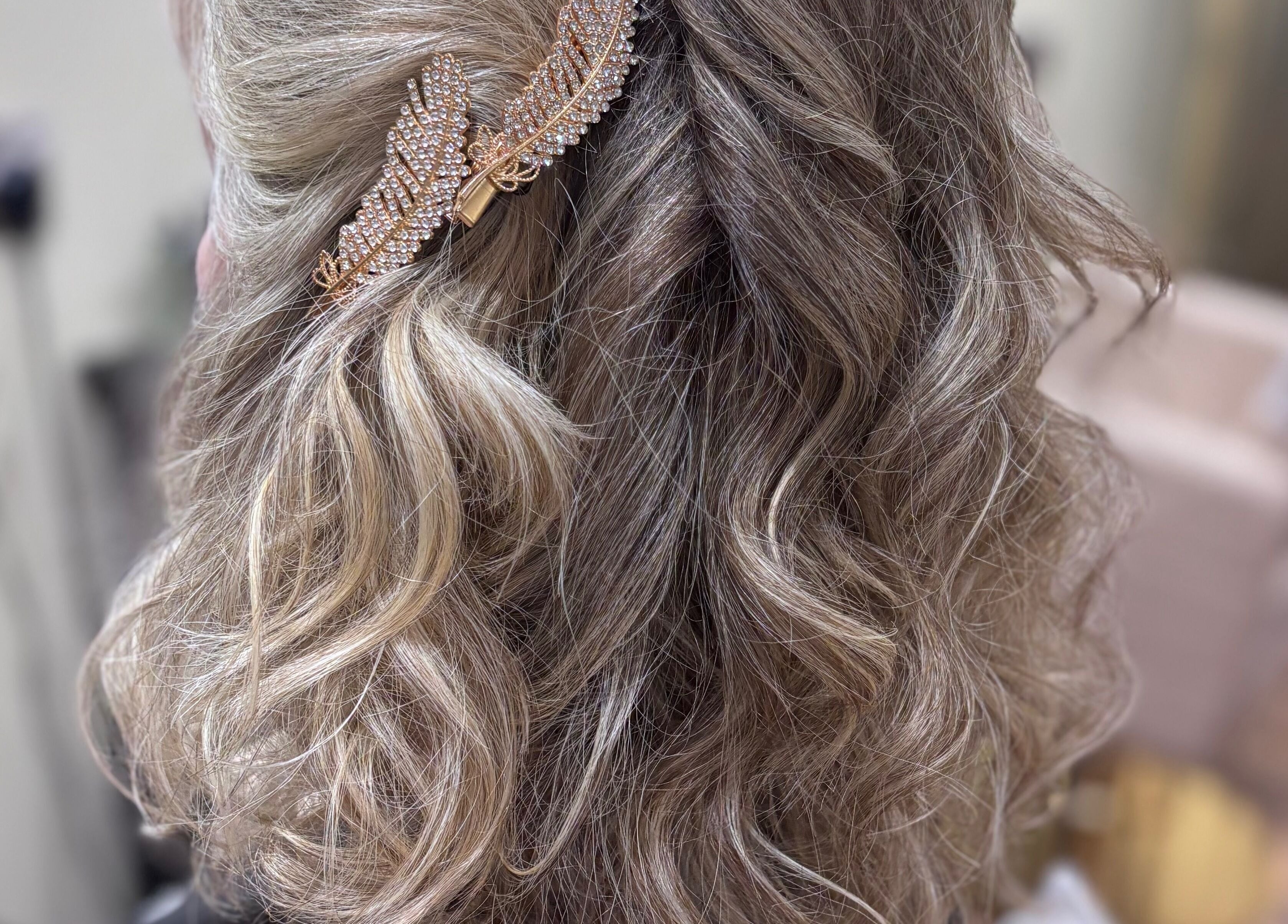 Stylish wavy blonde hairstyle with jewel accessory at Another Salon, Swansea, GB.