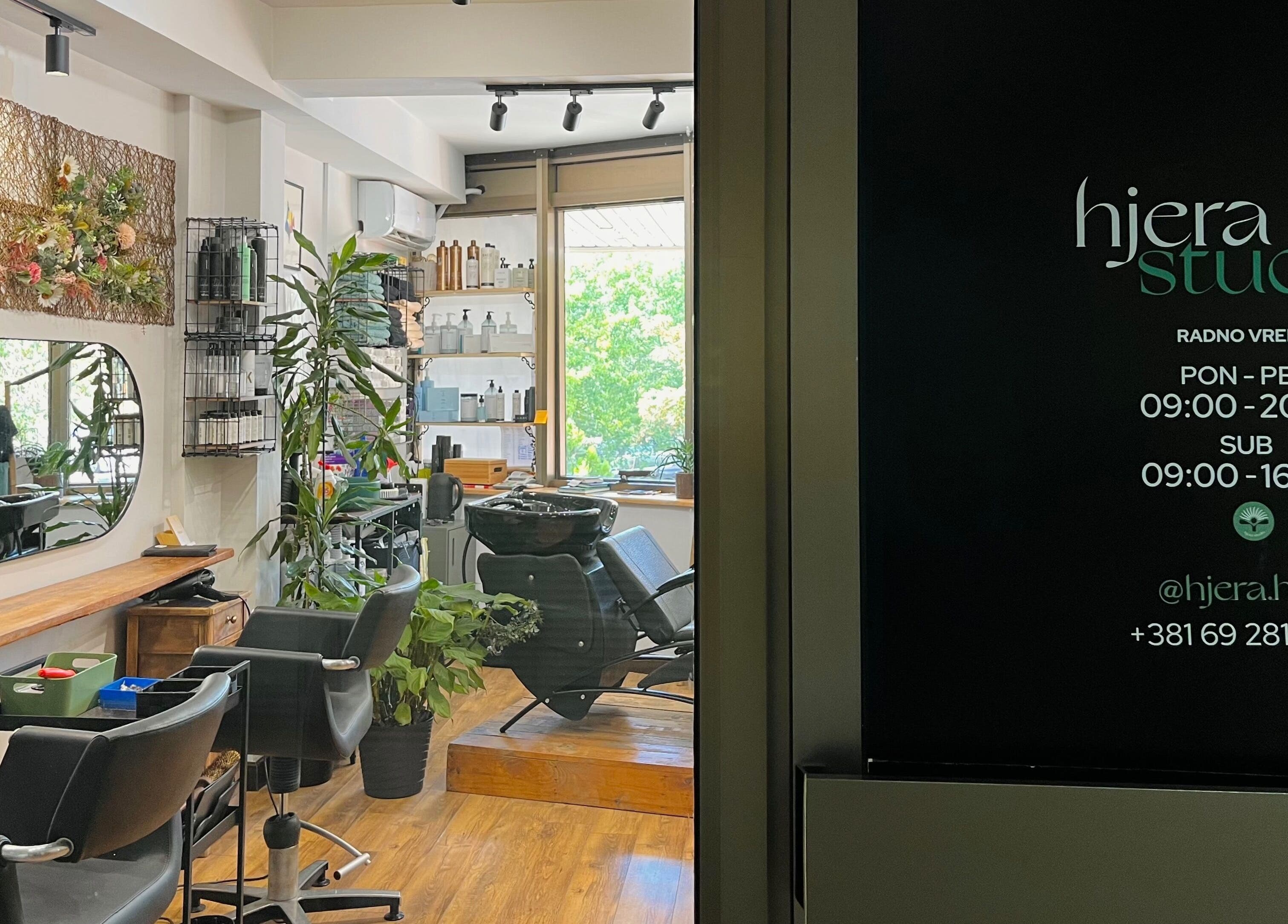 Chic interior of Hjera Studio & Spa, Beograd, RS showing modern salon setup with mirrors and greenery.