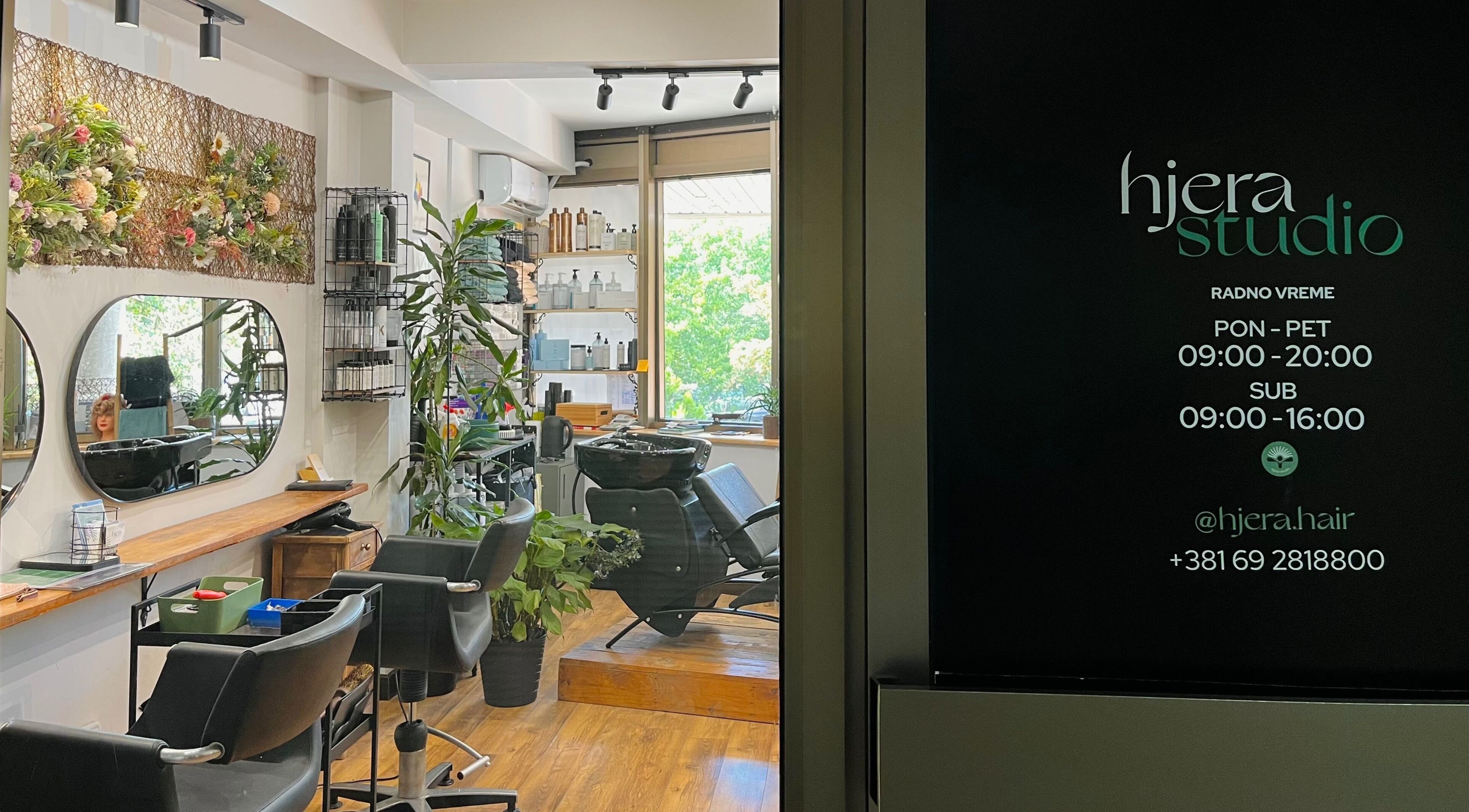 Chic interior of Hjera Studio & Spa, Beograd, RS showing modern salon setup with mirrors and greenery.