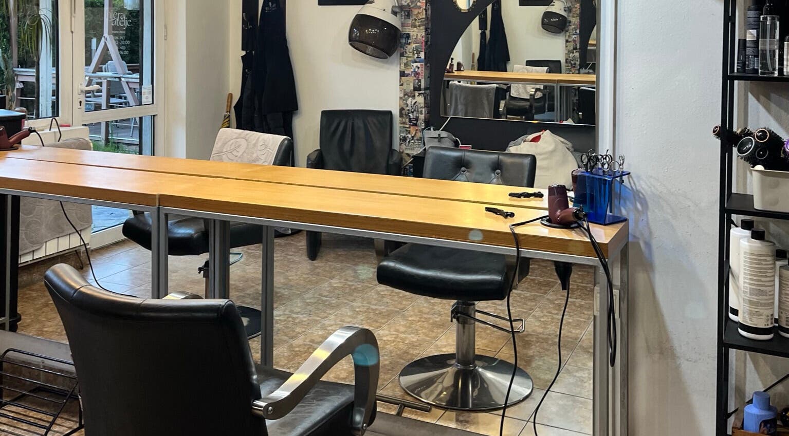 Modern salon interior at Hjera Atelje in Beograd, RS showcasing chairs, styling tools, and elegant decor.