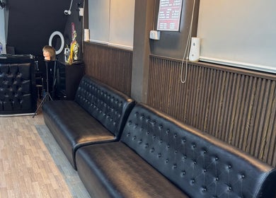 Interior moderno de D’Perú Barbershop en La Molina, Provincia De Lima, PE, con sofás de cuero negro.
