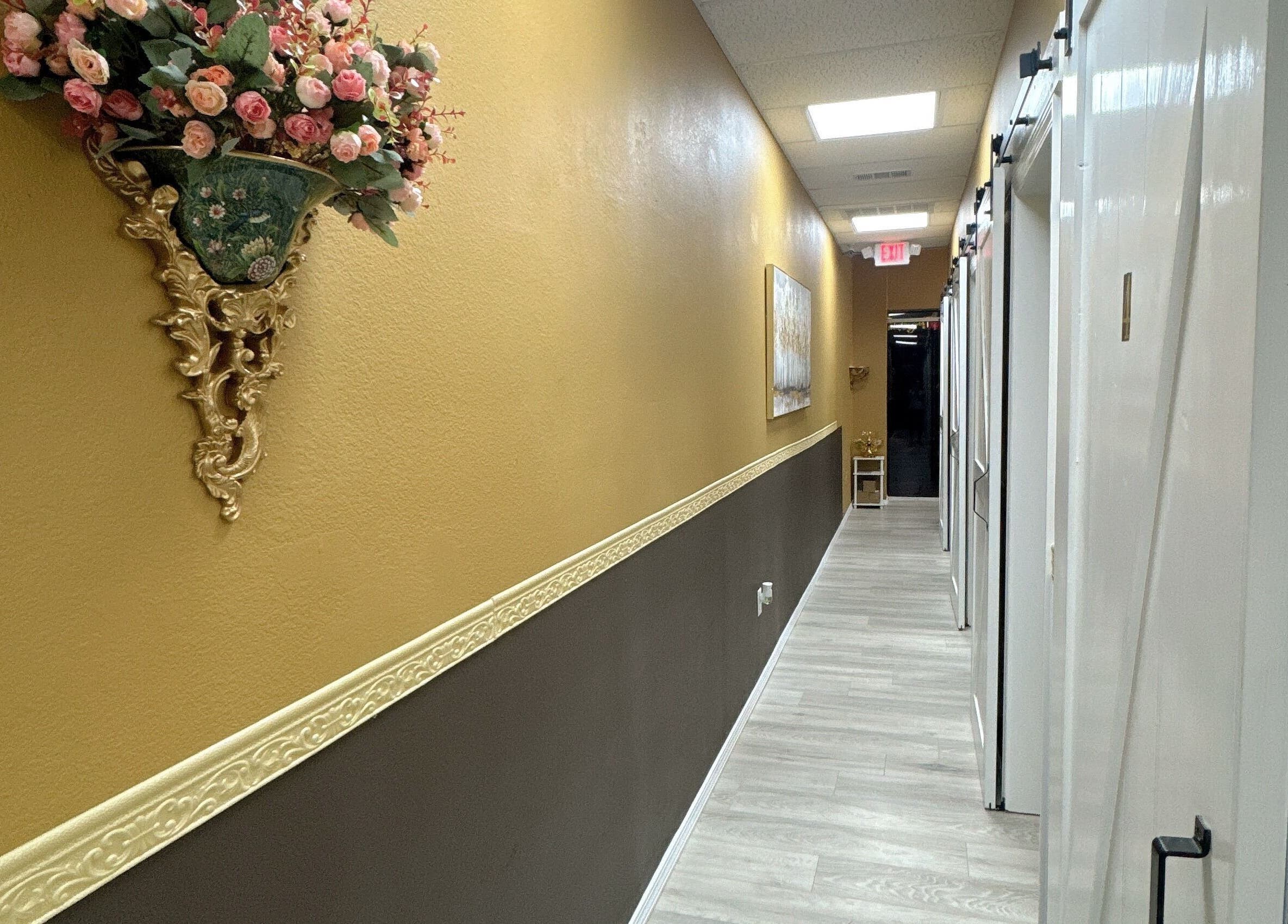 Elegant hallway at Oak Tree Massage & Facial Lovers ln, Dallas, Texas, US with gold decor and floral arrangement.