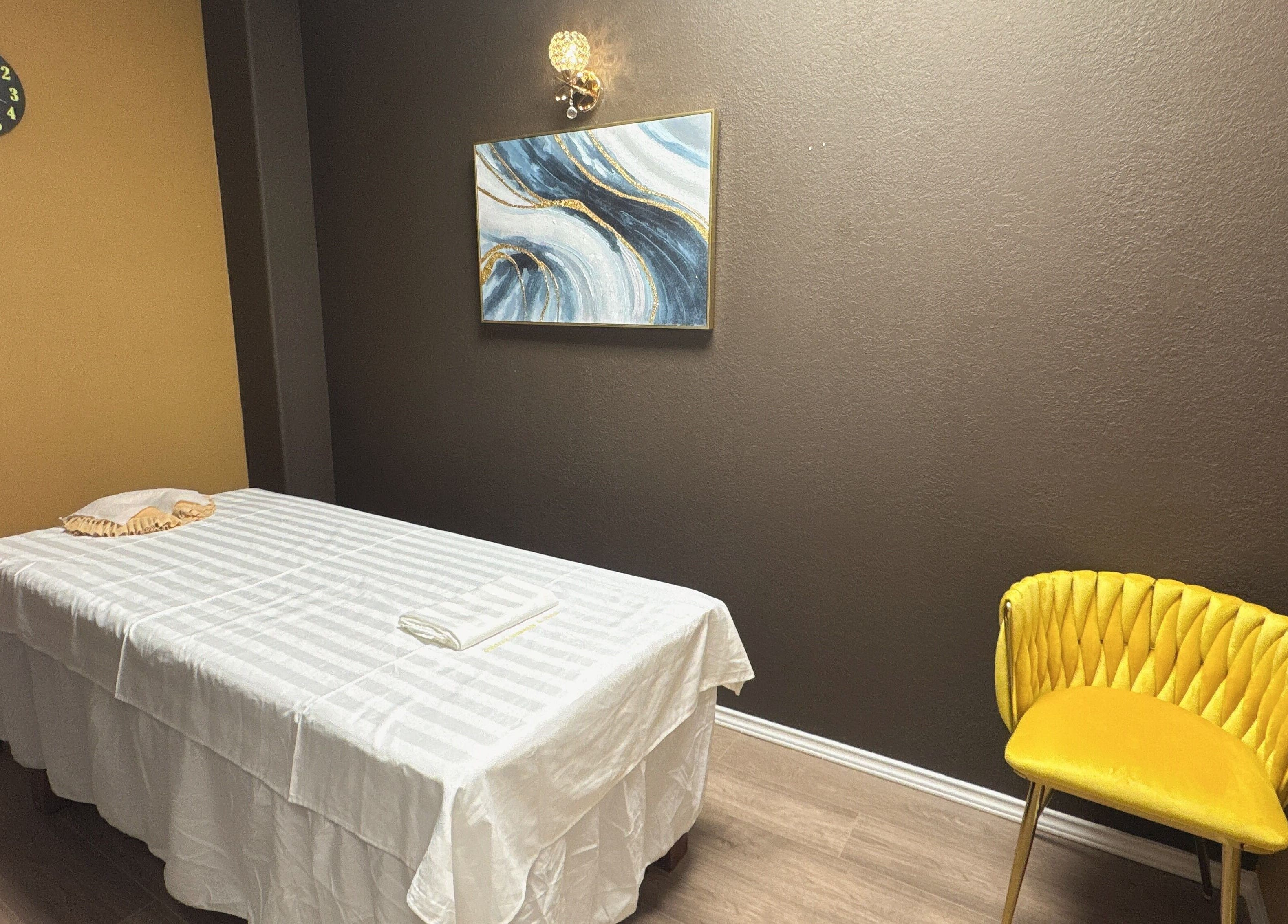 Serene massage room at Oak Tree Massage and Facial Frisco in Frisco, Texas, US with bed and chair.