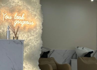 Stylish interior of Aaran Sutton Hair, Aberdeen, with cozy salon chairs and glowing wall decor.