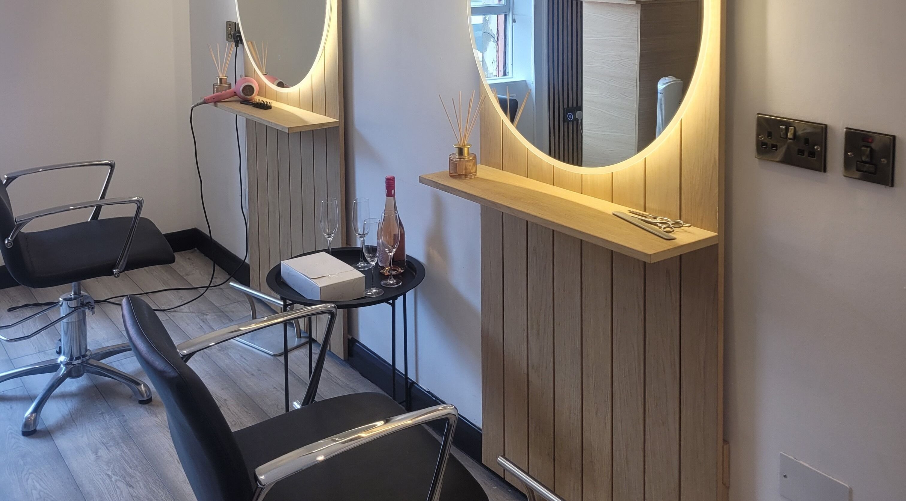 Modern styling station at The Hair Room, Dublin, County Dublin, IE, featuring sleek chairs and a lit mirror.