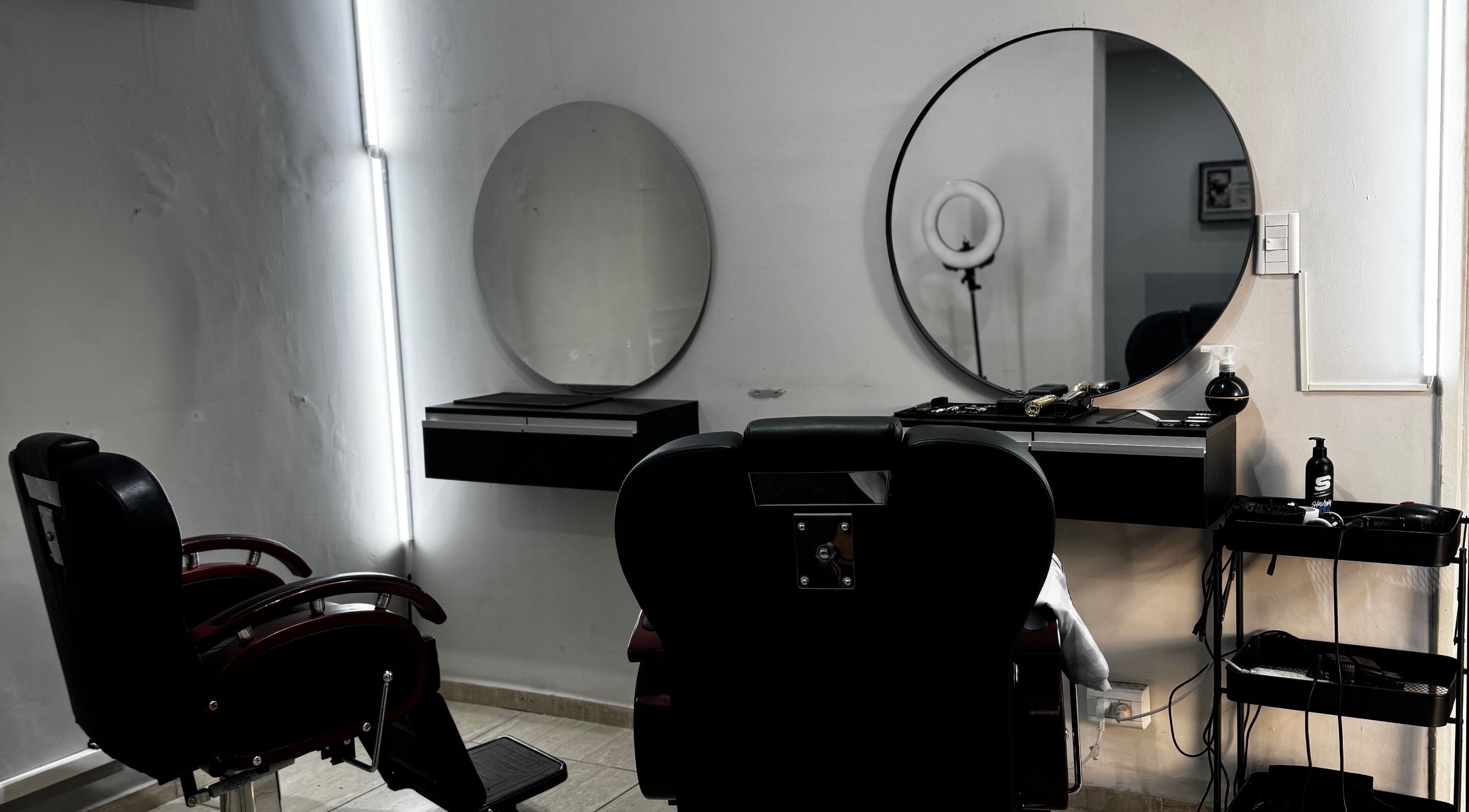 Sala de barbero en Francisco Miranda barber, San Juan, San Juan, AR, con espejo redondo y silla moderna.