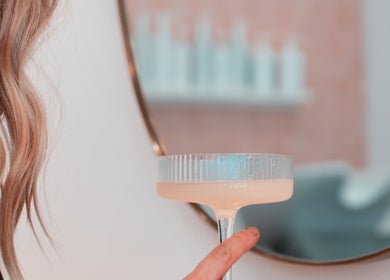A chic hair salon mirror and a hand holding a drink at HairyAdelaide, Mona Vale, New South Wales, AU.