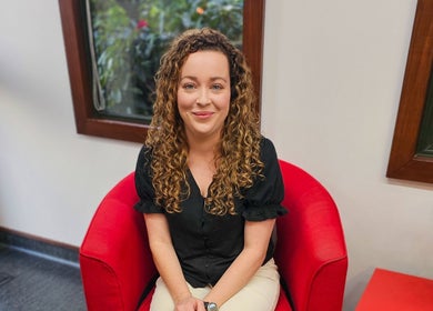 Person seated in a red chair at HairbyMrsBlades, Porirua, Wellington Region, NZ.