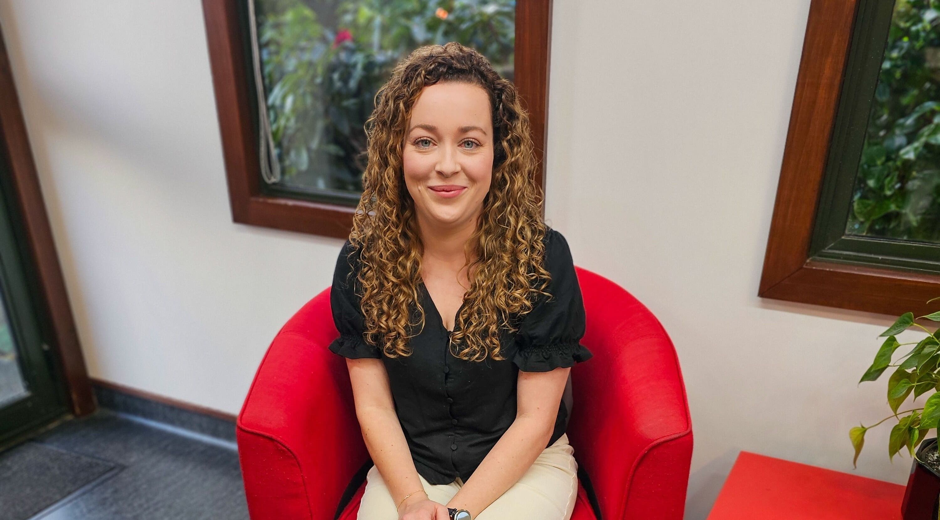 Person seated in a red chair at HairbyMrsBlades, Porirua, Wellington Region, NZ.