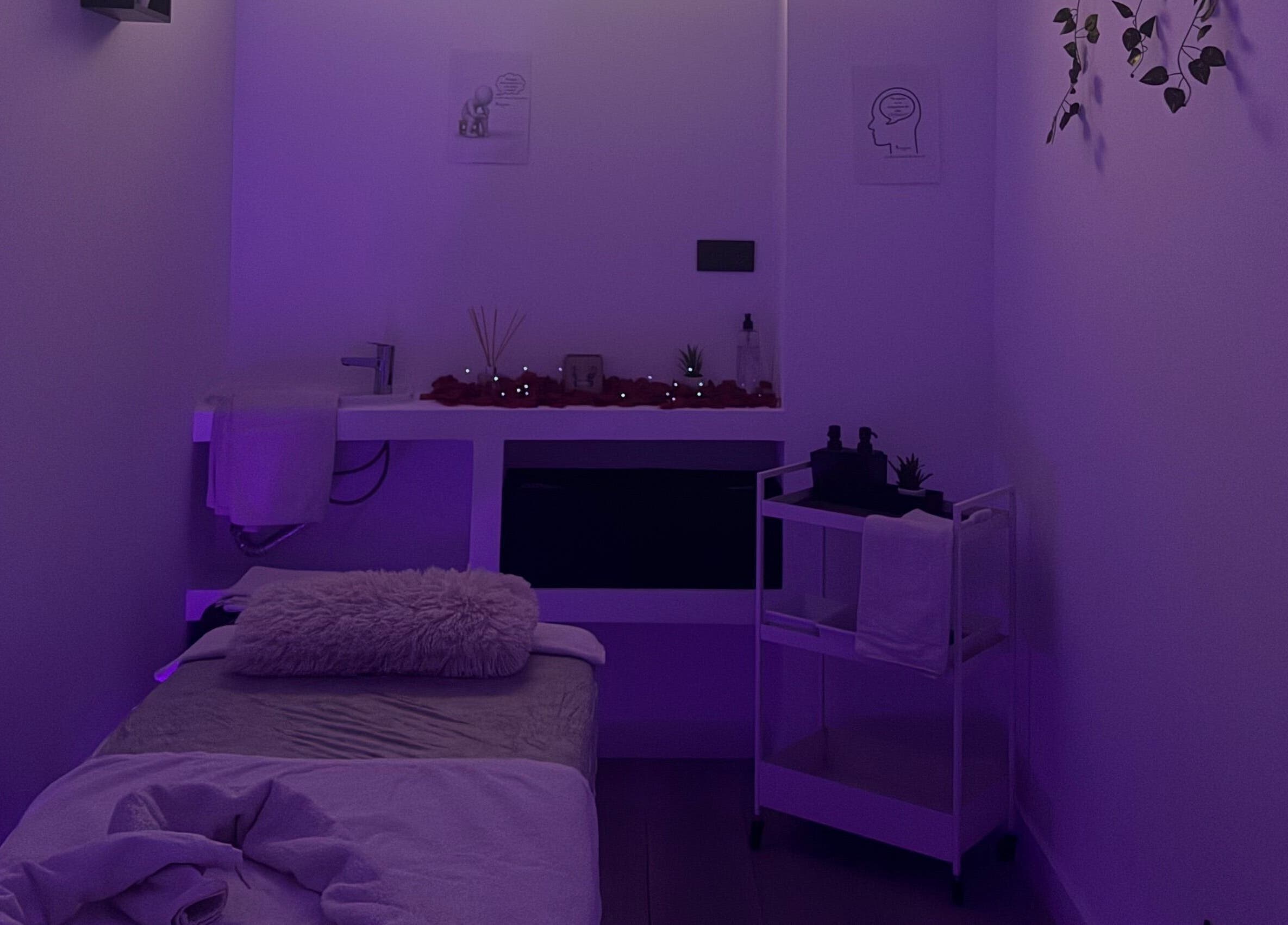 Sala de terapia tranquila en Clinica Raquel Salud, Alcorcón, Comunidad De Madrid, ES, con iluminación suave púrpura.