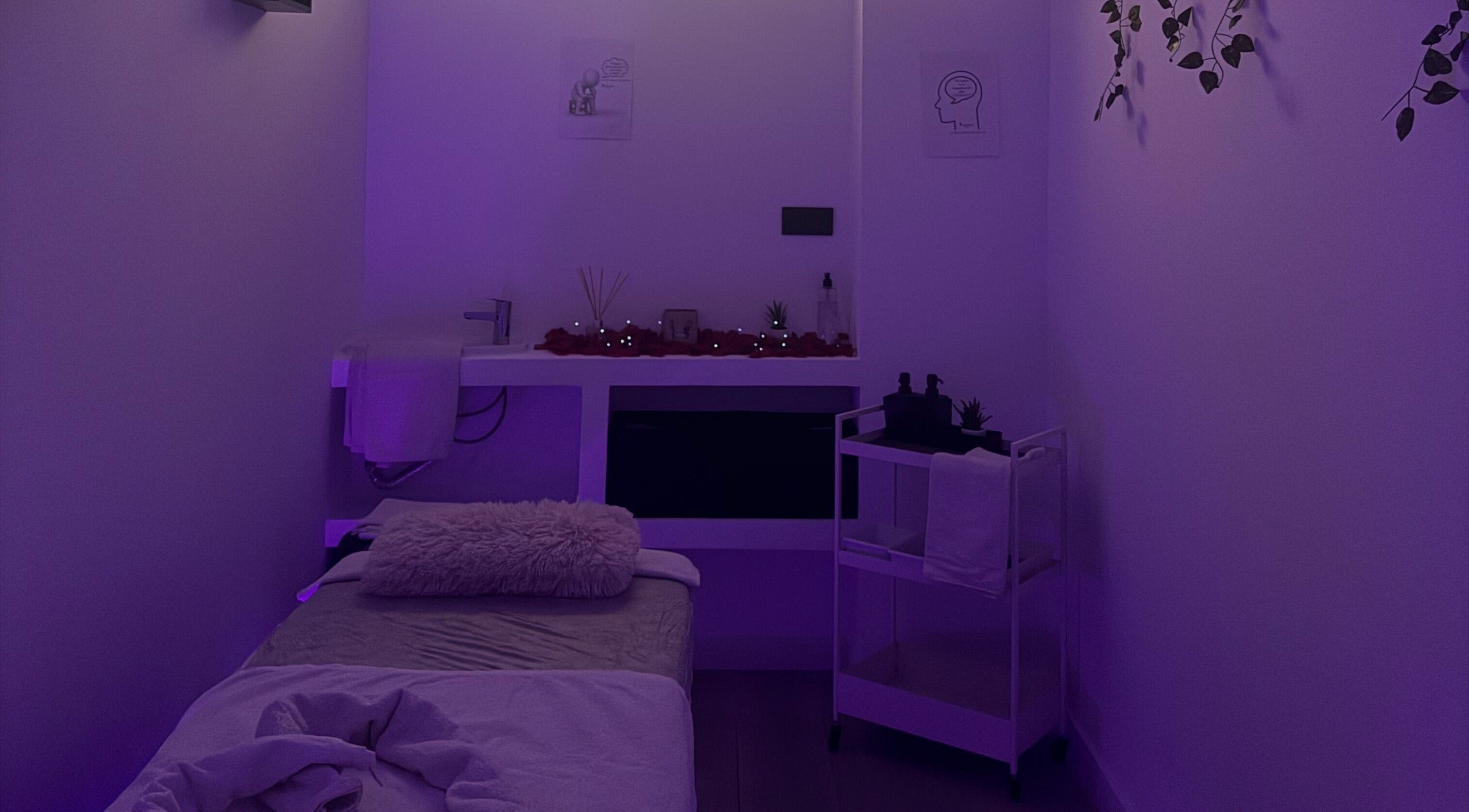 Sala de terapia tranquila en Clinica Raquel Salud, Alcorcón, Comunidad De Madrid, ES, con iluminación suave púrpura.