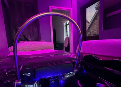 Relaxing massage room in soft purple light at CC Euphoria, Cape Town, ZA, featuring a cozy treatment table.